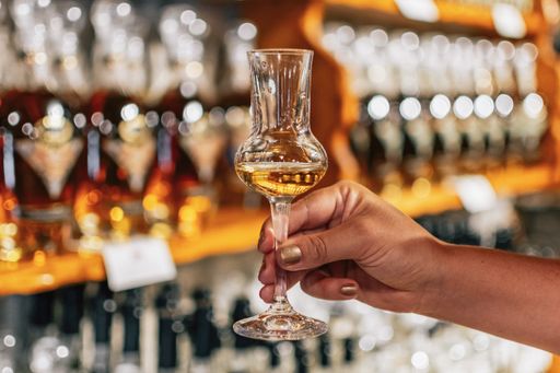 A shot of a female hand holding a glass filled with alcohol