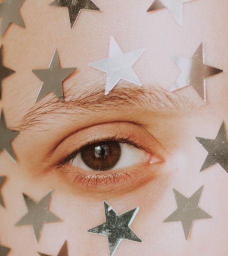 A closeup shot of a person's eye with silver stars around it