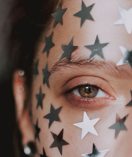 A shallow focus shot of a female beautiful eye with silver stars on her face