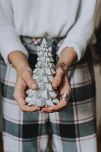 A vertical shot of a person holding a Christmas tree decoration