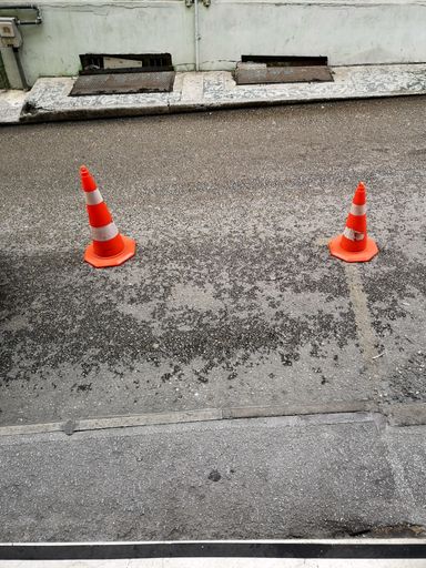 A vertical high angle shot of orange traffic cones on the street