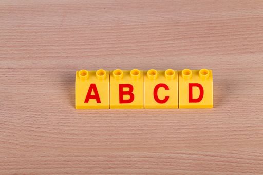 Several Lego parts with Latin letters on the wooden table
