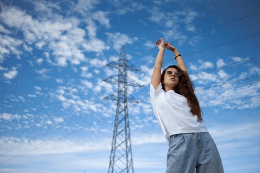 A low angle closeup portrait of a hipster cool Hispanic woman in stylish fancy sunglasses posing with her hands up in the air