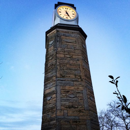 A vertical low angle shot of an old clock tower against the blue sky