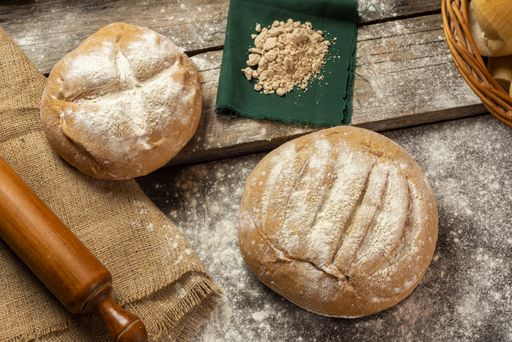 A top view of freshly baked homemade crusty pieces of bread with a rustic setting on a wooden board