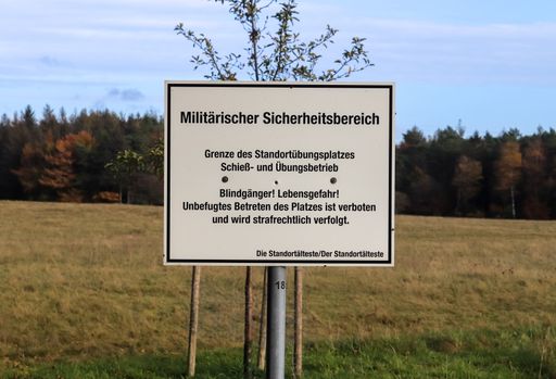 Warning sign in german language saying ' Duds, safety area - no entry' at a military training area.