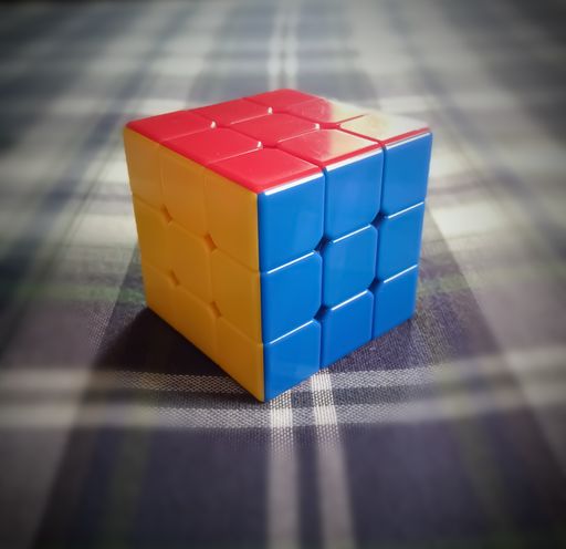 A closeup of a colorful Rubik's cube on a patterned surface