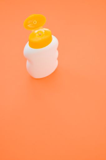 A top view closeup of a bottle with an opened yellow cap isolated on an orange background