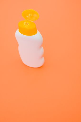 A top view closeup of a bottle with an opened yellow cap isolated on an orange background