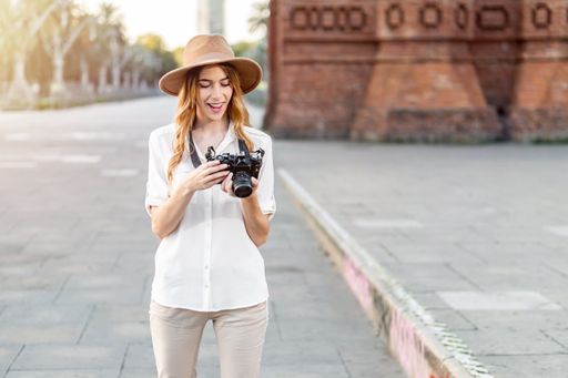 A shallow focus of a young female tourist with a fedora hat holding a camera in Barcelona, Spain
