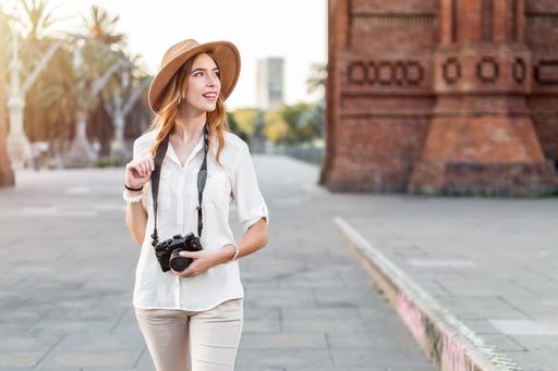 A shallow focus of a young female tourist with a fedora hat holding a camera in Barcelona, Spain