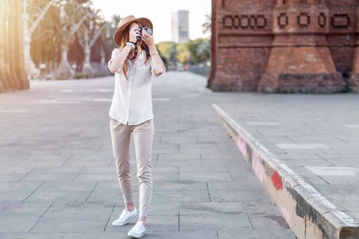 A shallow focus of a young female tourist with a fedora hat taking pictures in Barcelona, Spain