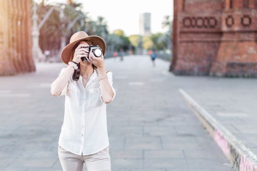 A shallow focus of a young female tourist with a fedora hat photographing in Barcelona, Spain