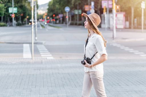 Woman professional photographer exploring the streets with a vintage camera in hand. Female tourist enjoying a vacation in Europe