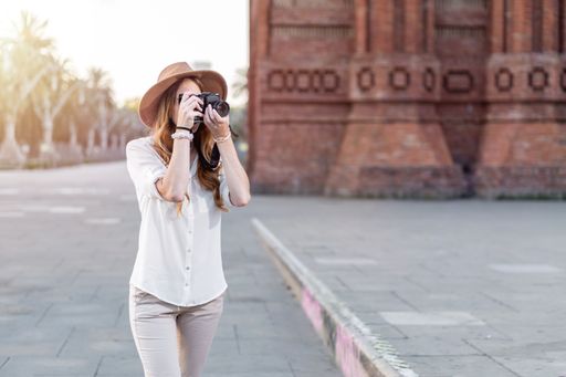 Tourist woman taking pictures of the city. Professional female photographer  using a vintage camera to take photos outdoors.