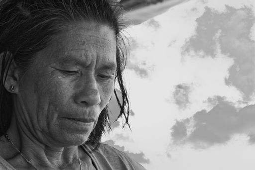 A greyscale shot of elderly female preparing food under an outside canopy in the Philippines