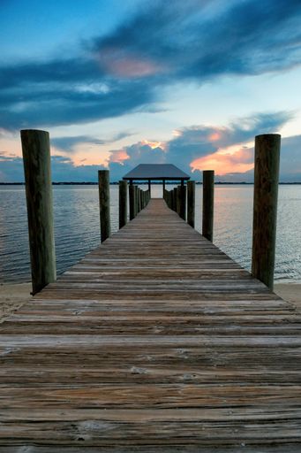A wooden bridge in the sea under a cloudy sky during sunset - a cool picture for wallpapers