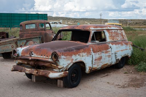 An old abandoned Ford Courier Sedan Delivery, rusty and with bullet holes