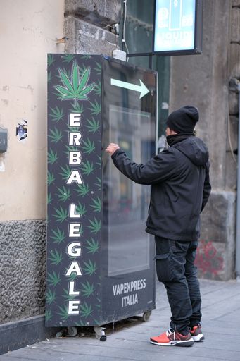 A vertical shot of a male using the vending machine with the text "erba legale" in Naples, Italy