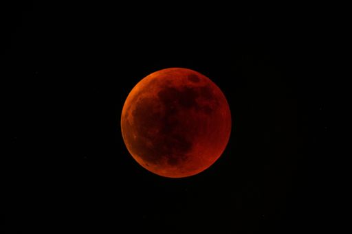 A closeup shot of a red moon isolated on a black background