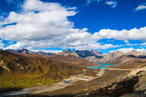 An aerial shot of the rocky mountains with a river and blue sky in the background, Xizang, Tibet, China