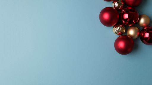 A top view of shiny Christmas tree ornaments on a light blue background with a copy space