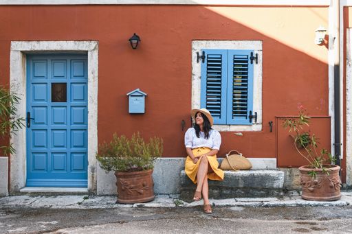 a white caucasian sitting on a stone bench by a red house