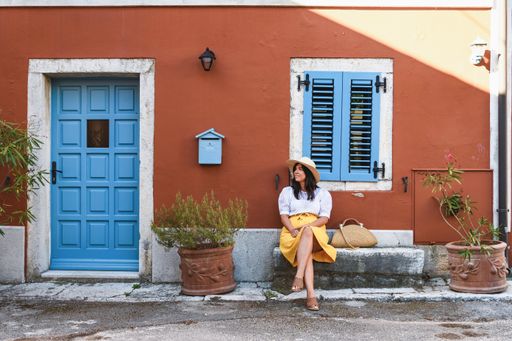 a white caucasian sitting on a stone bench by a red house