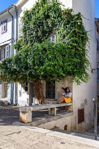 a vertical shot of a white caucasian woman lying on the stone bench under a tree