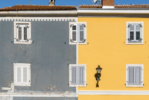a half yellow half gray building with white windows
