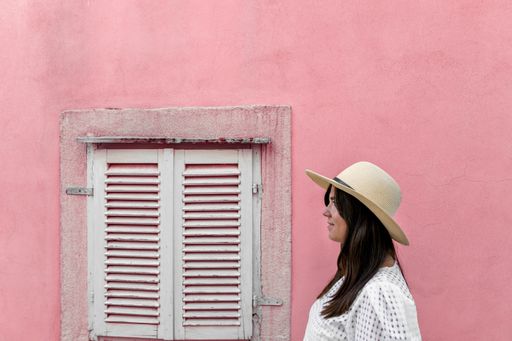 a side view of a white caucasian woman on the background of a pink wall with a white window
