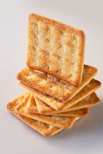 A pile of seven sugar-coated sweet crackers with one standing on top