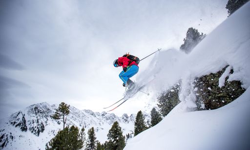 A low angle shot of a man skiing in the Austrian alps with snowy mountain peaks in the background
