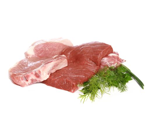 A closeup shot of raw pork meat with green herbs isolated on white background