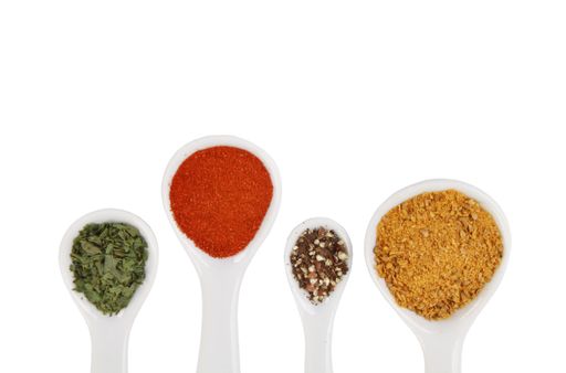 A closeup top view shot of various spices on a white surface