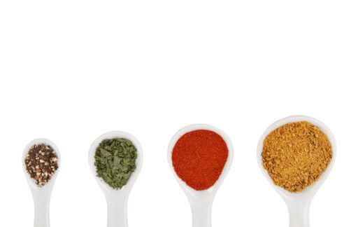 An overhead shot of a collection of spices on spoons isolated on white background