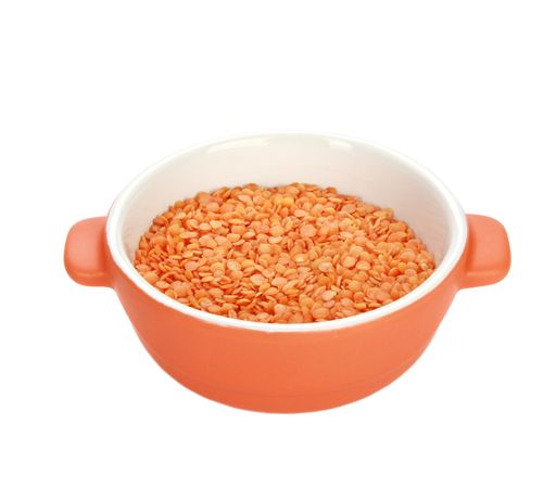 A vertical high angle shot of raw lentils in a ceramic bowl on a white background