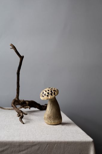 A vertical shot of a wooden mushroom decor on a table covered in a white cloth