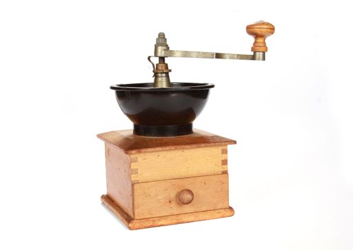 A closeup shot of an antique coffee grinder on a white background
