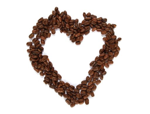A top view of heart-shaped roasted coffee beans on a white surface