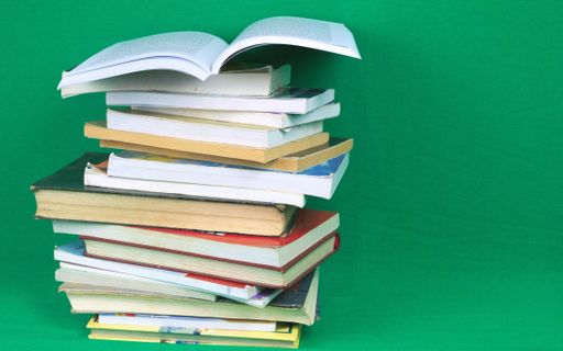 A closeup shot of books stacked on top of each other on green background