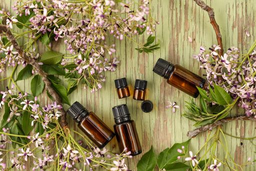 A top view shot of little bottles with oil for aromatherapy surrounded by dry flower leaves