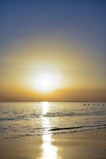 A vertical shot of a beach reflecting the sunlight under a blue sky