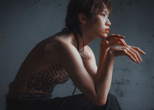 A portrait of a sad pretty East Asian female with English texts on her naked body
