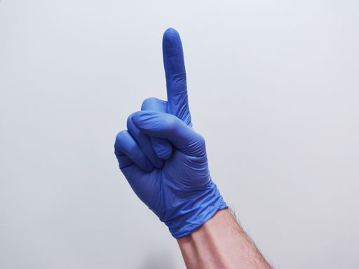 A closeup shot of a male hand in a glove pointing up a finger
