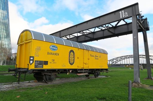 A yellow banana railroad wagon monument on the banks of the river Main in front of the ECB