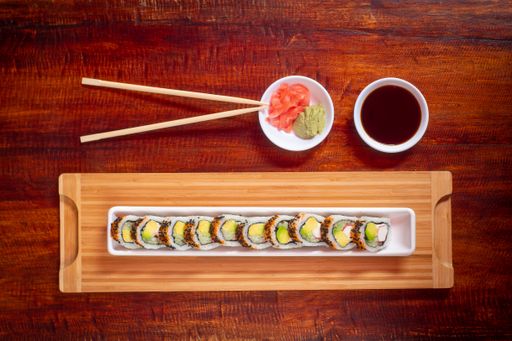Delivery Style Asian Food Consisting of Avocado and Rice Sushi with Crab Eggs Around Served with Soya Sauce, Pickled Ginger, Wasabi and Sticks