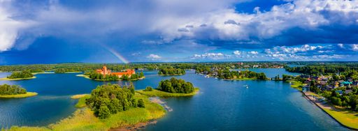An aerial shot of an amazing lake surrounded by green forests and an island with an old castle