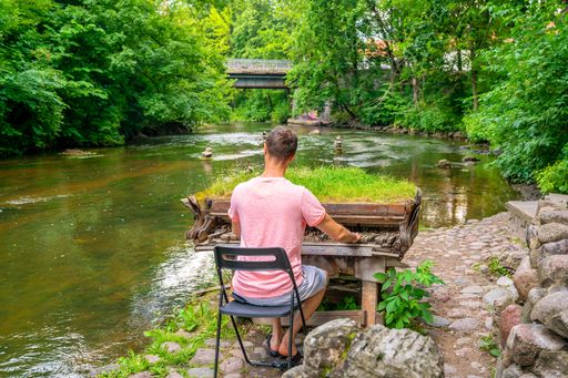 An amazing shot of a young man playing piano on the river background