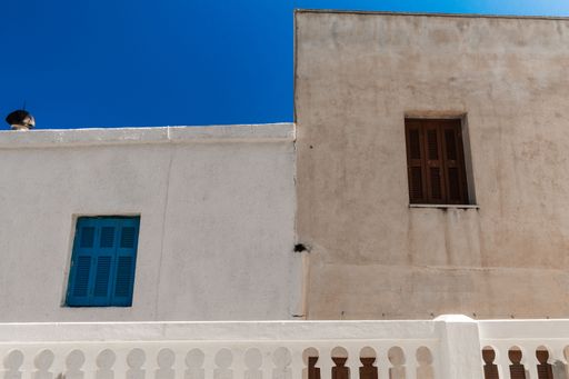 The old building walls with small windows against the background of the blue sky. Greece.